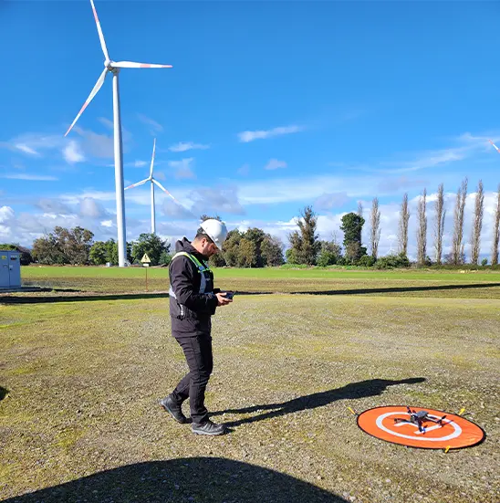 Persona operando dron en parque eólico para inspección