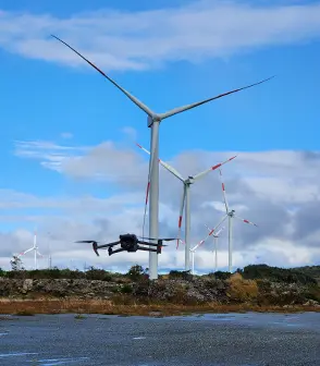 Dron en vuelo frente a aerogeneradores en parque eólico